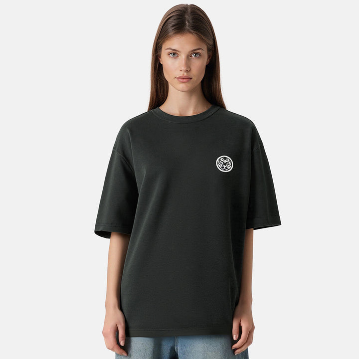 Person wearing a black t-shirt with a small logo on a plain background