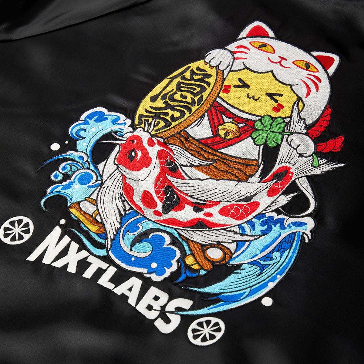 Embroidered design on a black fabric with a fish, umbrella, and character, featuring the brand 'NXT LABS'.
