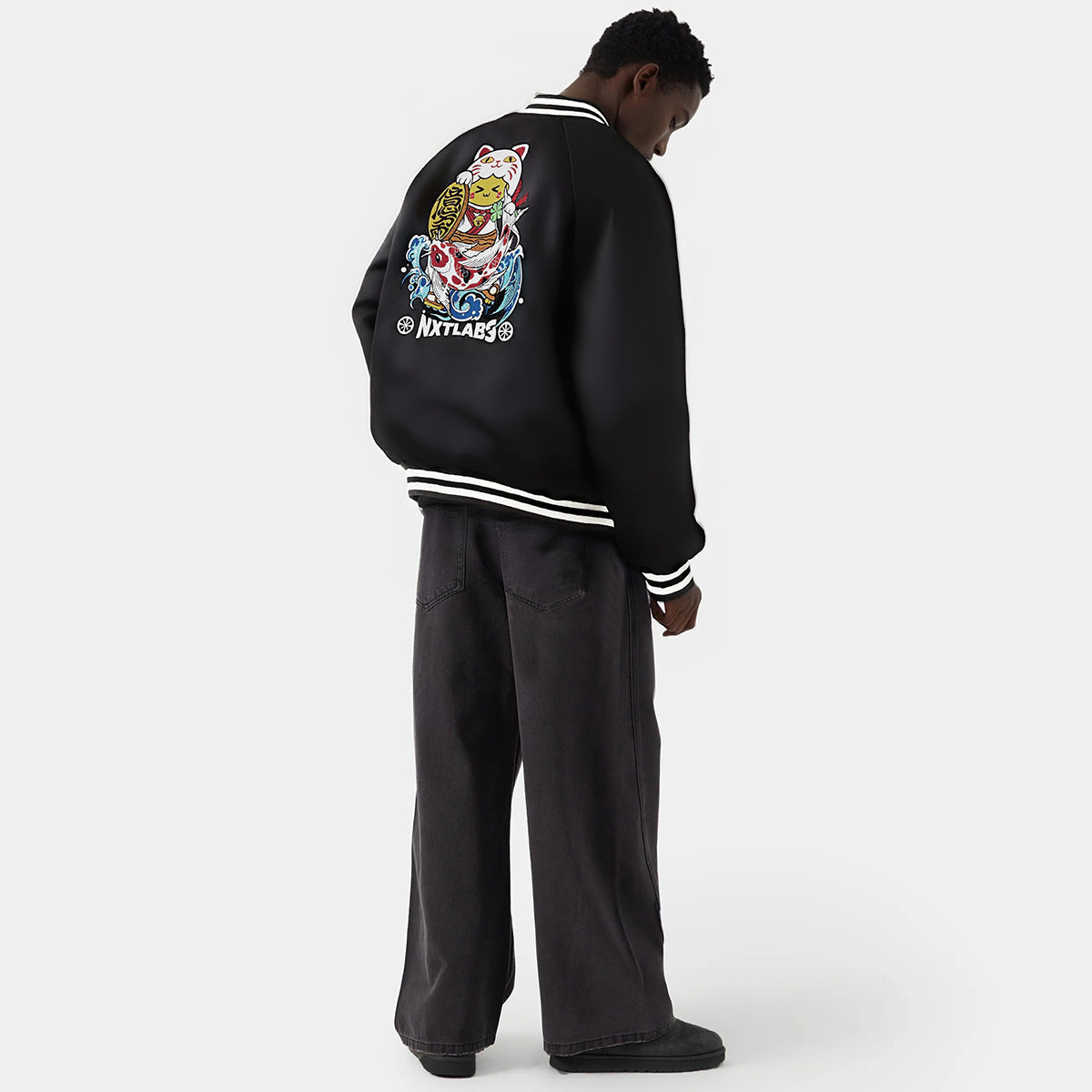 Person wearing a black jacket with colorful graphics on the back, standing against a white background