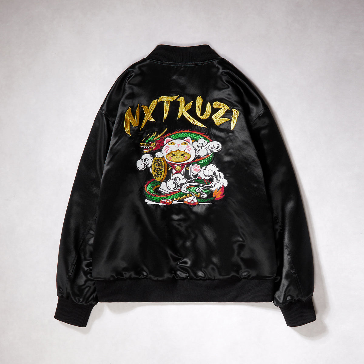 Black satin jacket with colorful embroidery and 'NXTKUZI' branding on a white background