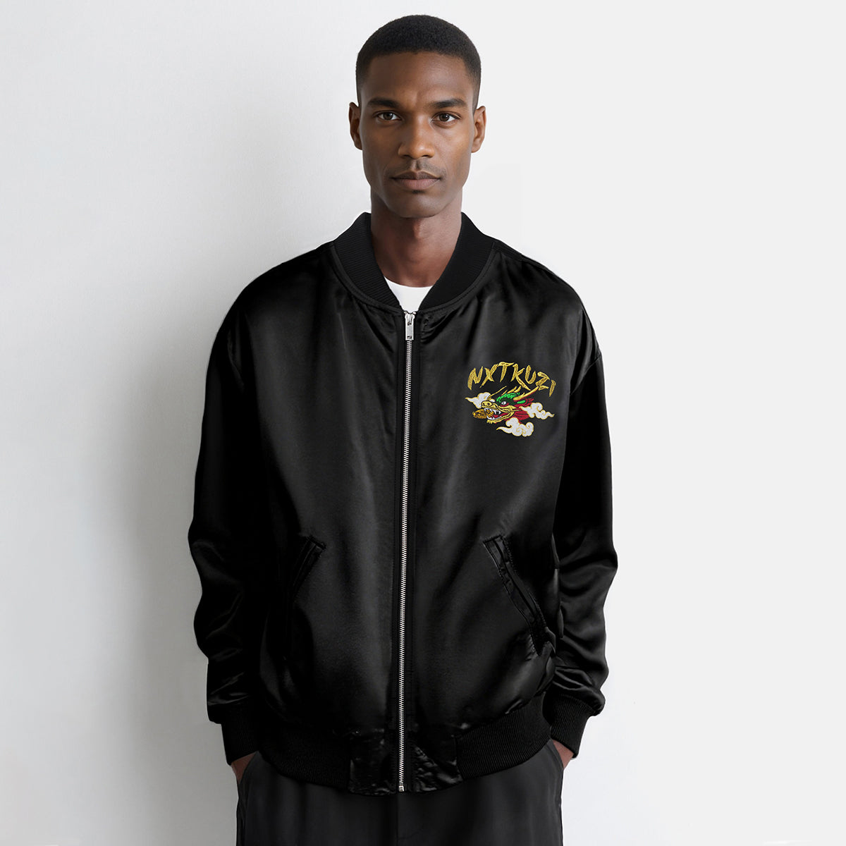 Man wearing a black bomber jacket with a logo on a white background
