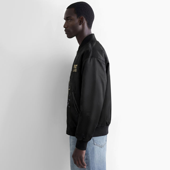 Person wearing a black jacket with a logo on a white background